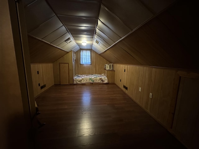 additional living space with dark wood-type flooring, lofted ceiling, and wood walls