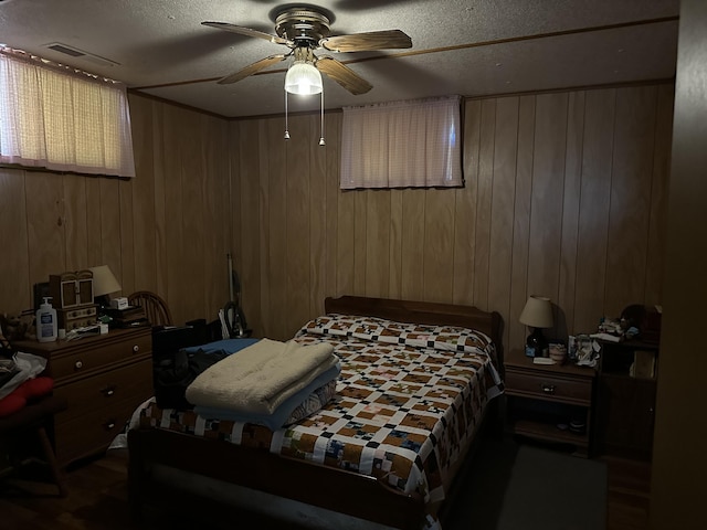 bedroom featuring ceiling fan, wood walls, and a textured ceiling