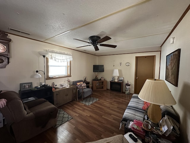 living room featuring ceiling fan, dark hardwood / wood-style flooring, a textured ceiling, and ornamental molding