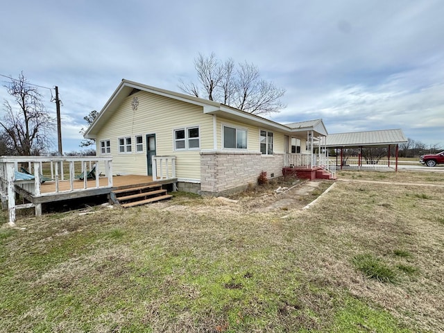 back of house with a deck, a carport, and a lawn