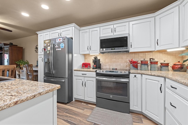 kitchen with tasteful backsplash, appliances with stainless steel finishes, and white cabinetry