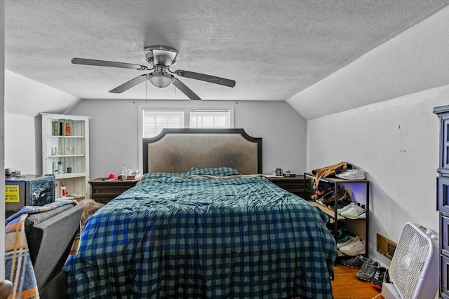 bedroom featuring ceiling fan, hardwood / wood-style flooring, a textured ceiling, and lofted ceiling