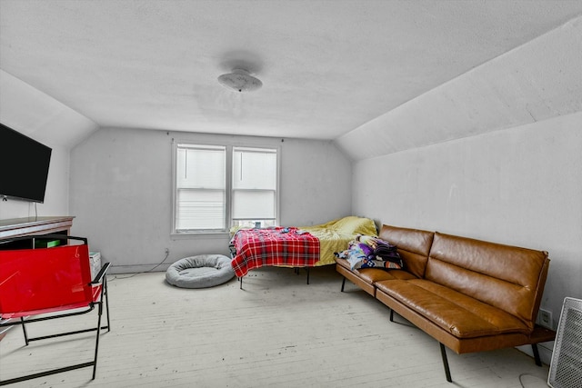 bedroom featuring hardwood / wood-style floors, a textured ceiling, and vaulted ceiling