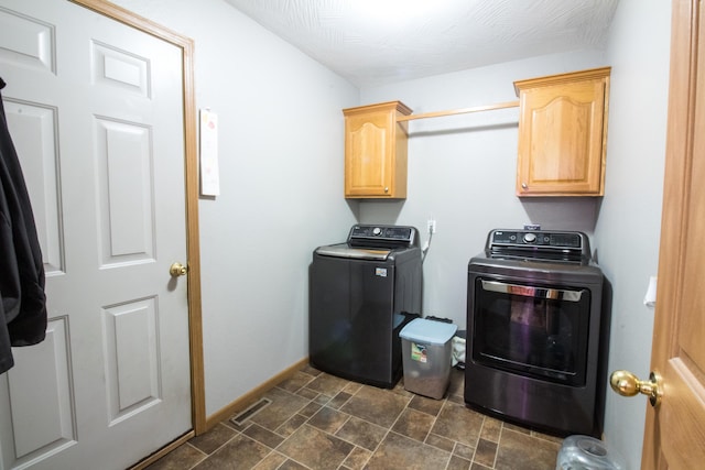 clothes washing area featuring washing machine and dryer and cabinets