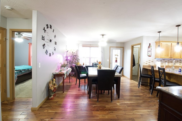 dining space with ceiling fan, dark wood-type flooring, and sink