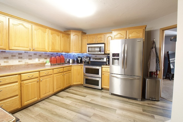 kitchen with decorative backsplash, stainless steel appliances, and light wood-type flooring