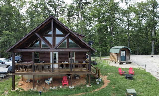 back of house featuring a wooden deck, a lawn, and a storage shed