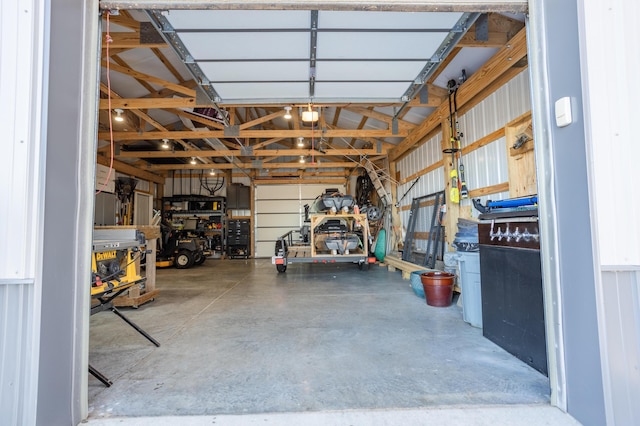 garage with a workshop area, a garage door opener, and metal wall