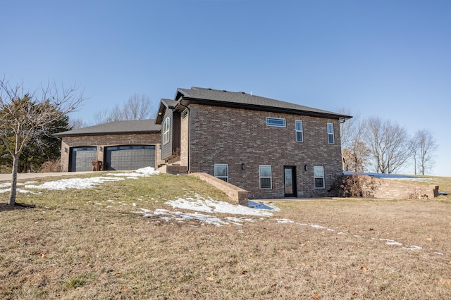 view of side of home with brick siding, an attached garage, and a yard