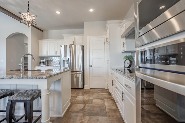 kitchen featuring backsplash, pendant lighting, appliances with stainless steel finishes, white cabinets, and a sink