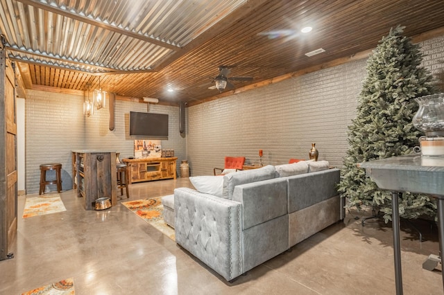 living room featuring ceiling fan, concrete floors, and brick wall