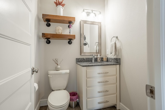 bathroom featuring baseboards, toilet, and vanity