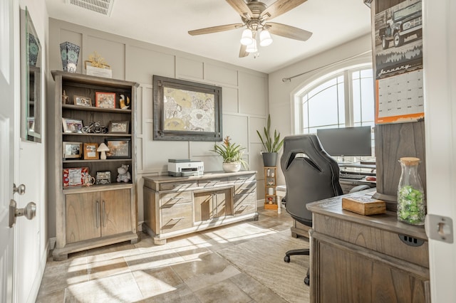 office space with visible vents, a decorative wall, and ceiling fan