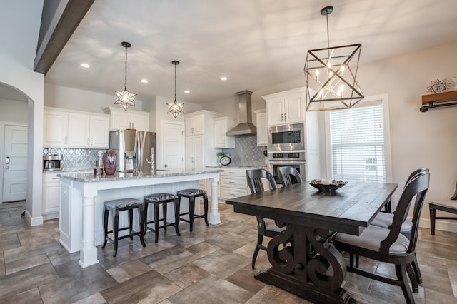 dining room featuring recessed lighting, baseboards, and arched walkways