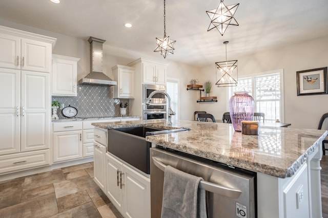 kitchen featuring white cabinetry, a sink, stainless steel dishwasher, wall chimney range hood, and backsplash