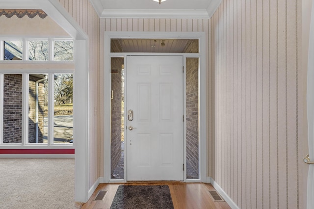 foyer with crown molding and light hardwood / wood-style floors