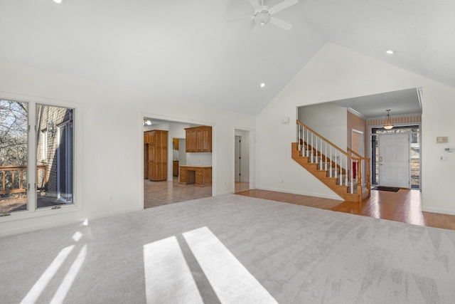 unfurnished living room featuring ceiling fan, light colored carpet, and high vaulted ceiling