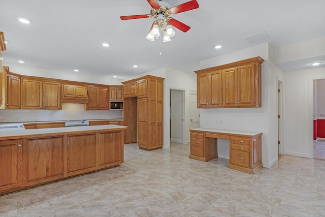 kitchen with sink, built in desk, ceiling fan, decorative backsplash, and stove