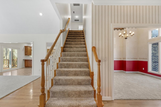 staircase featuring hardwood / wood-style flooring, a wealth of natural light, and an inviting chandelier