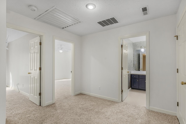 corridor featuring light carpet and a textured ceiling