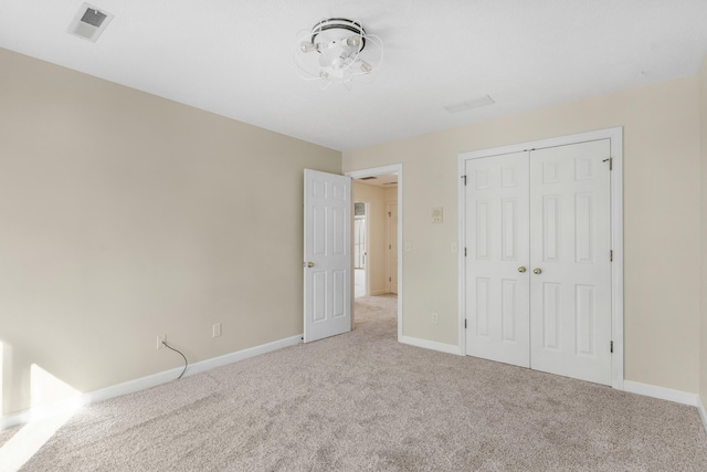 unfurnished bedroom featuring light colored carpet and a closet