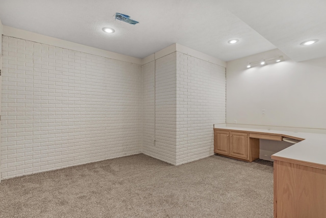 unfurnished office featuring light colored carpet, brick wall, and built in desk