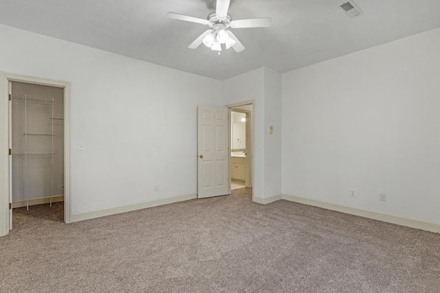 unfurnished bedroom featuring ceiling fan, a closet, a spacious closet, and carpet