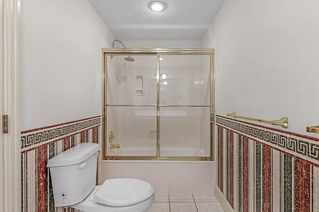 bathroom featuring enclosed tub / shower combo, tile patterned floors, and toilet