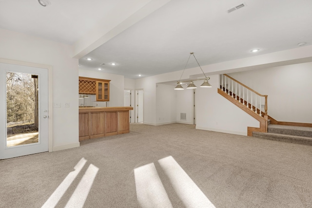 unfurnished living room with light carpet and bar area