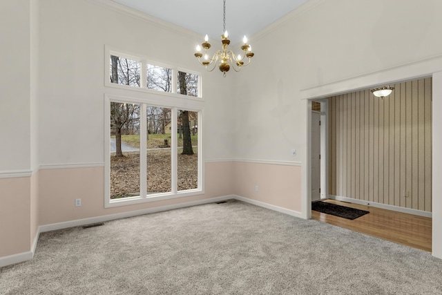 carpeted empty room featuring crown molding, a chandelier, and a high ceiling