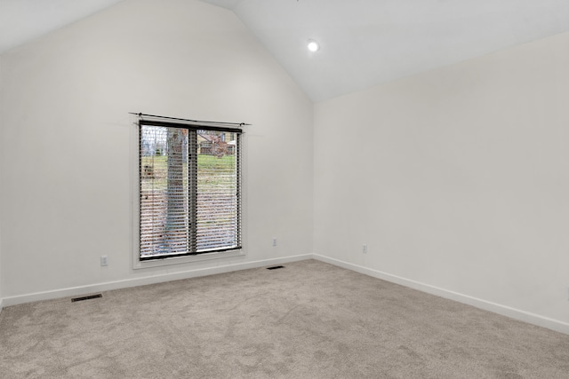 carpeted empty room with high vaulted ceiling