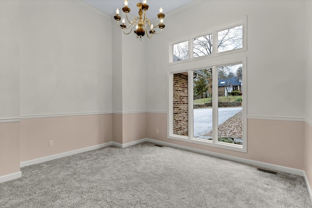 empty room featuring crown molding, a chandelier, and carpet