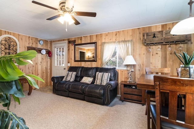 carpeted living room featuring ceiling fan and wood walls