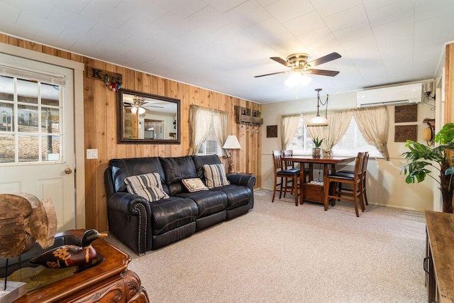 carpeted living room with ceiling fan, a healthy amount of sunlight, wooden walls, and a wall unit AC