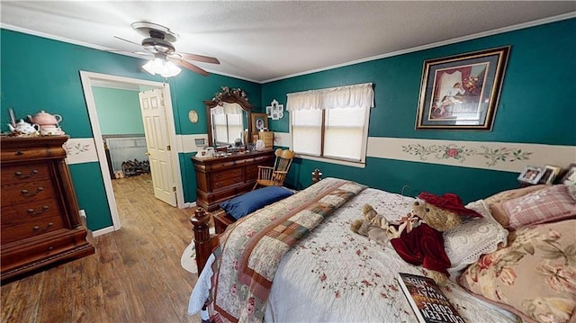 bedroom with a spacious closet, ceiling fan, a closet, wood-type flooring, and crown molding