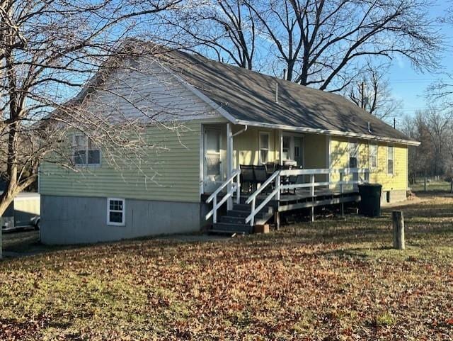 back of property featuring a wooden deck and a lawn