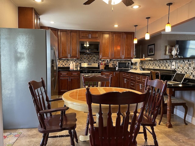 kitchen featuring ceiling fan, appliances with stainless steel finishes, backsplash, and hanging light fixtures