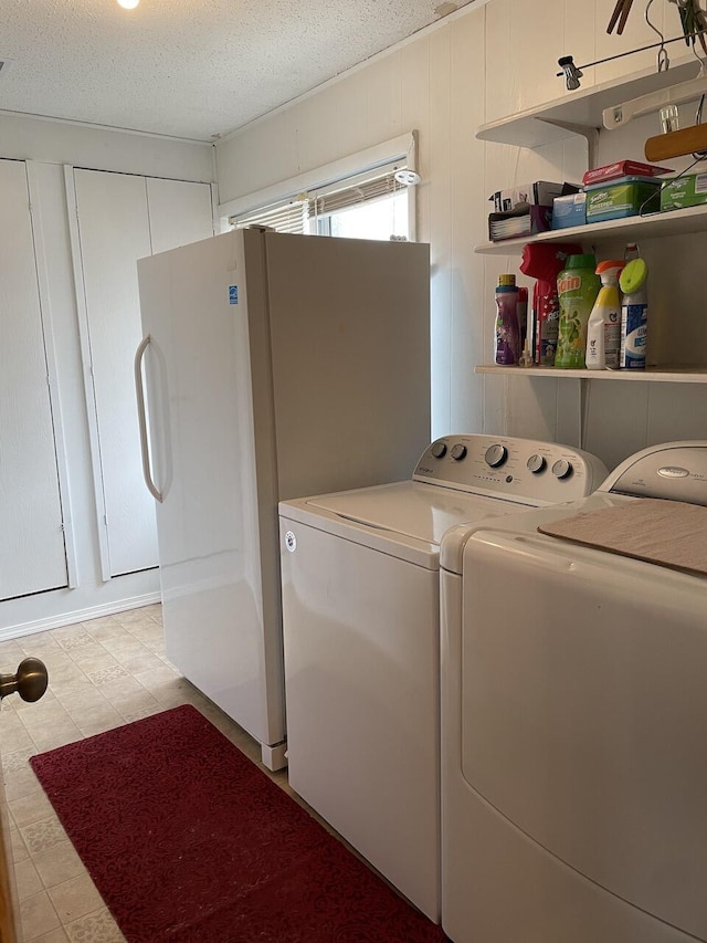 clothes washing area with washing machine and dryer and a textured ceiling