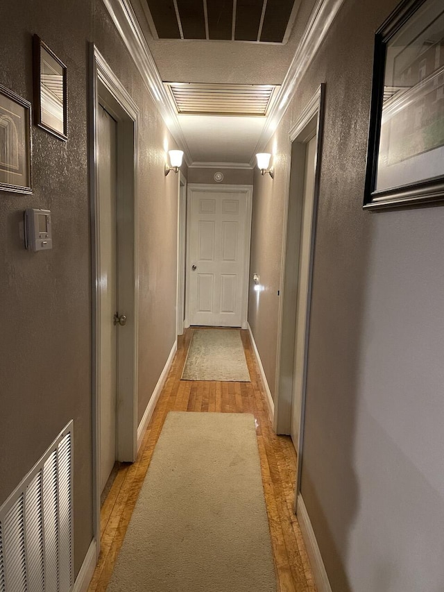 hall with ornamental molding and light hardwood / wood-style flooring