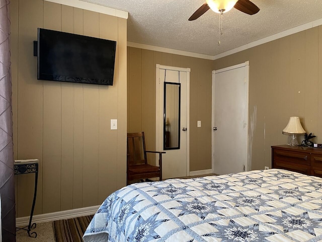 bedroom featuring ceiling fan, a textured ceiling, wood walls, and crown molding