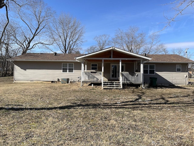 back of property featuring central AC unit, covered porch, and a yard