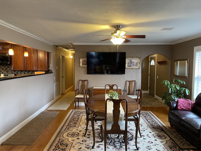 dining room with ceiling fan, crown molding, a textured ceiling, and light hardwood / wood-style floors