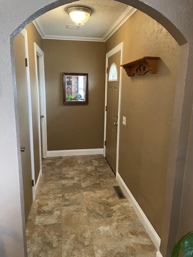 hall with a textured ceiling and ornamental molding