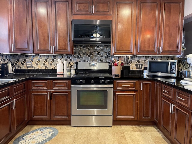 kitchen featuring decorative backsplash, light tile patterned floors, appliances with stainless steel finishes, and dark stone counters