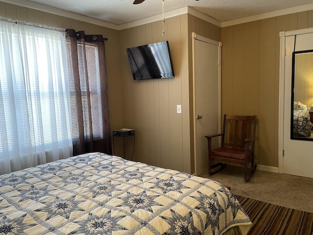 bedroom featuring carpet, ceiling fan, crown molding, and a textured ceiling