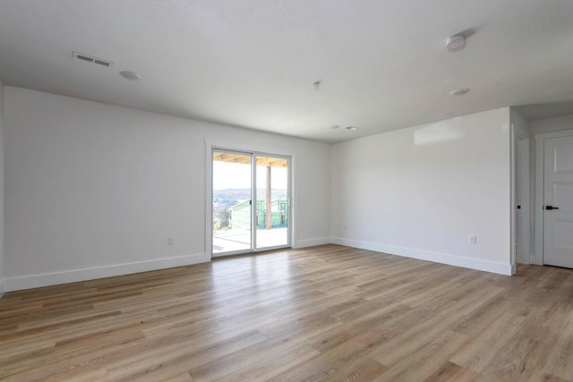 spare room with visible vents, light wood-style flooring, and baseboards