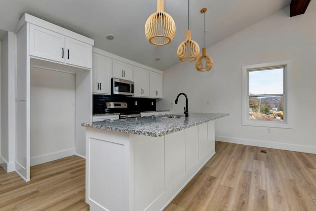 kitchen with tasteful backsplash, white cabinets, appliances with stainless steel finishes, vaulted ceiling, and a sink