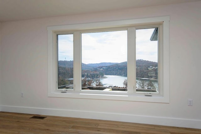 room details featuring baseboards, visible vents, a water and mountain view, and wood finished floors