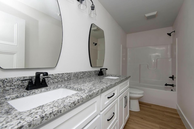 full bathroom featuring wood finished floors, shower / tub combination, a sink, and toilet