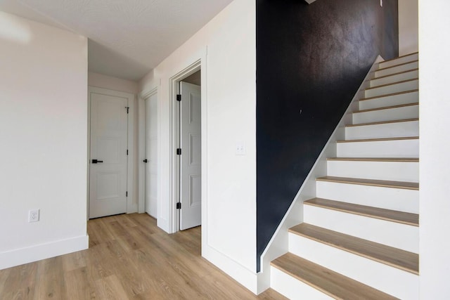 staircase featuring baseboards and wood finished floors